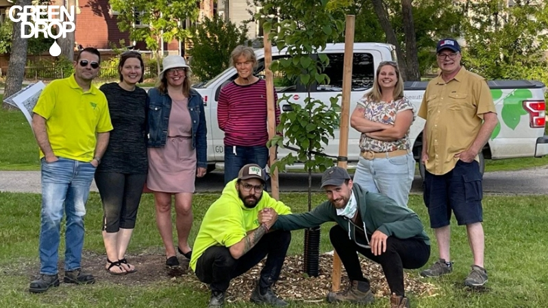 Green Drop workers posing in front of a newly planted tree with customers