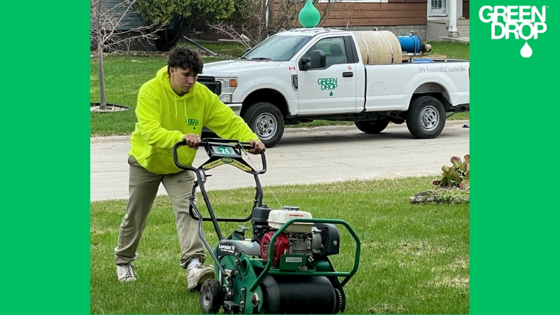 Green Drop employee aerating a lawn with a company truck in the back