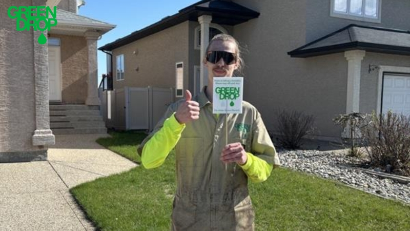 Green Drop employee holding a company sign and giving a thumbs up