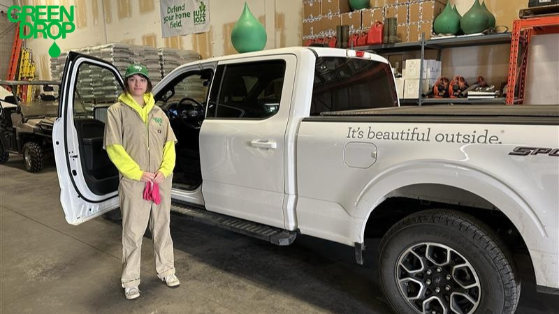 Green Drop employee posing in front of a company truck in a garage