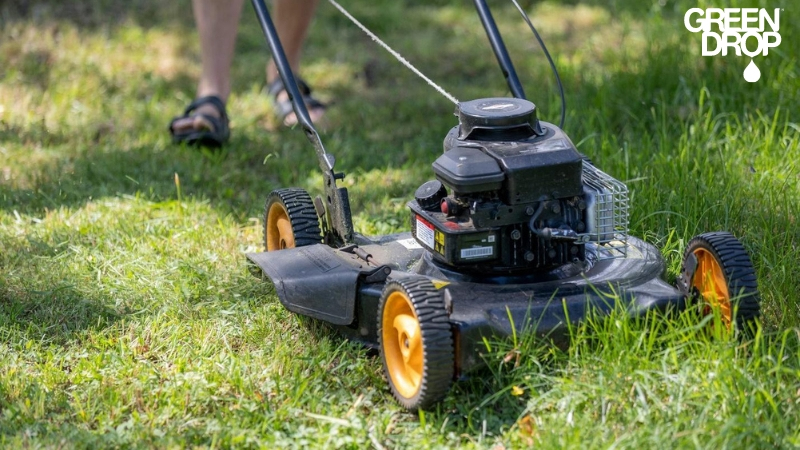 Close up shot of a green drop employee mowing lawn