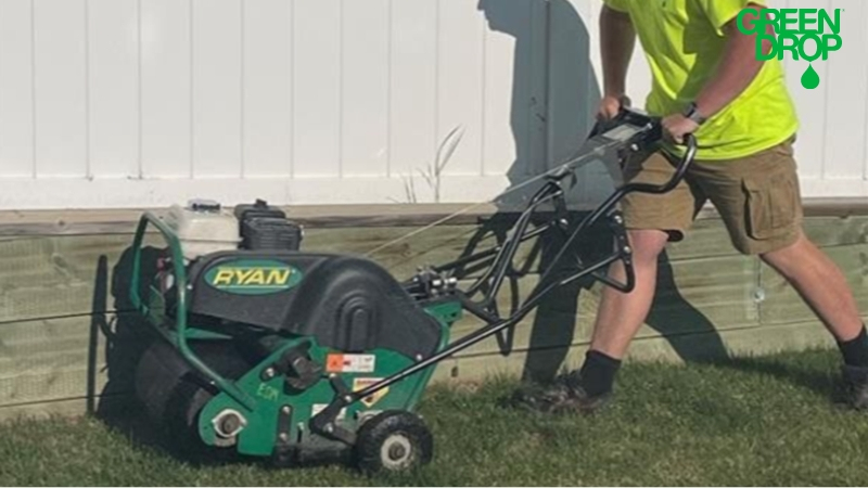 Green Drop worker using aeration tool on a lawn